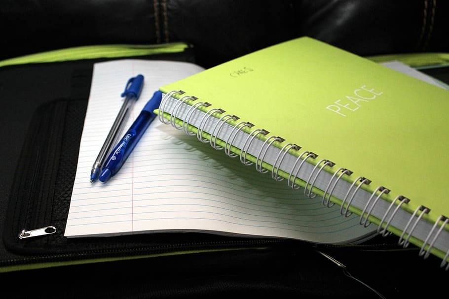 A green notebook, paper and pencils