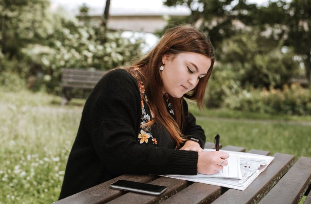 girl sitting on a bench and writing